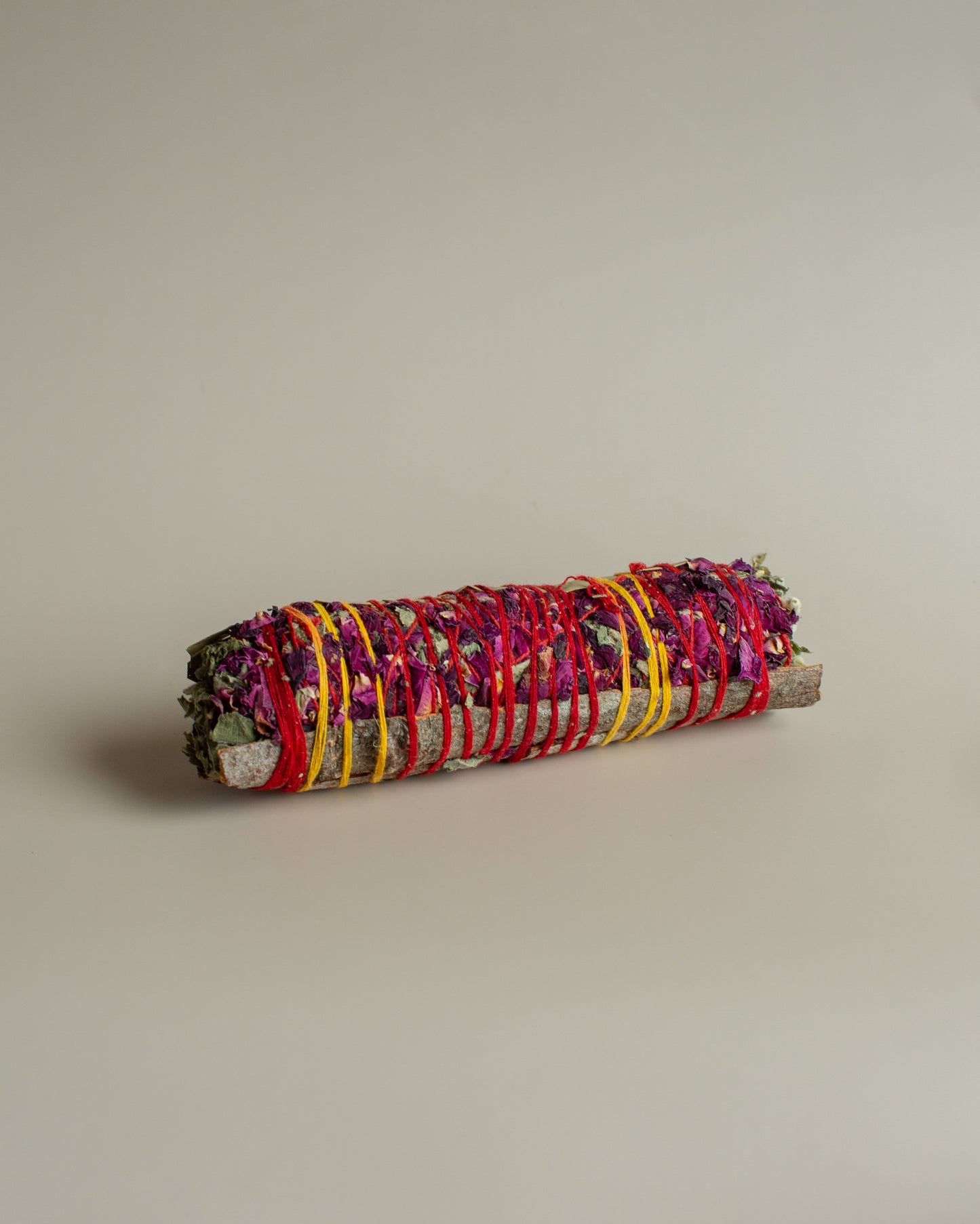Rolled bundle of incense sticks with colorful ribbons on a beige background