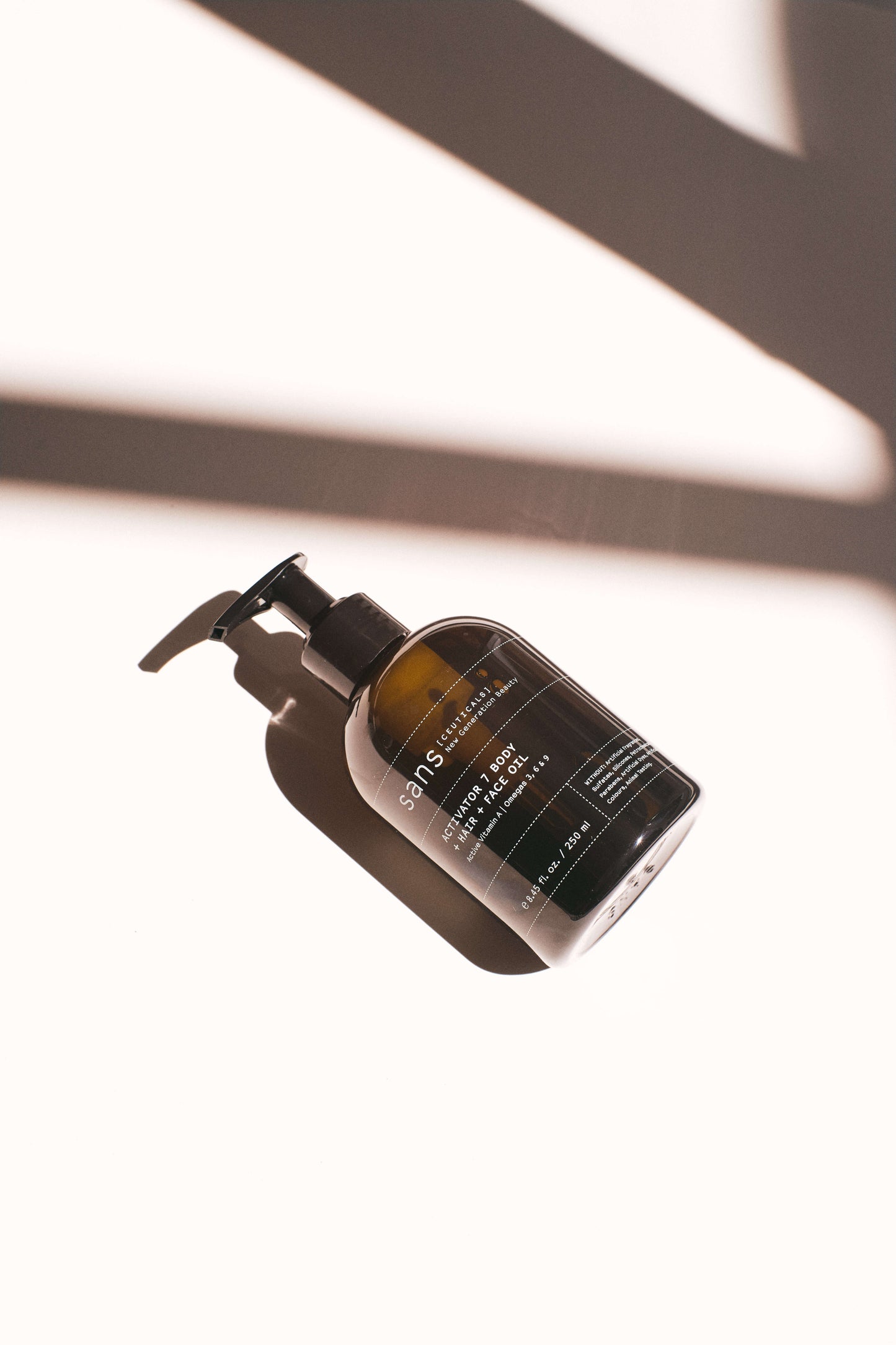 Skincare bottle with pump on a white background with shadows from the sun