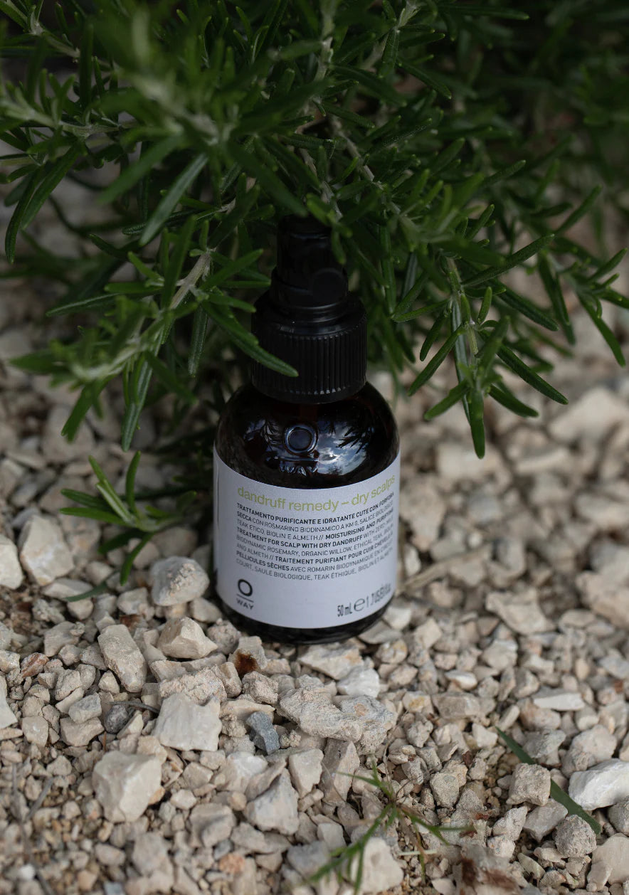 Bottle of Oway Dandruff Remedy on a stone surface with greenery