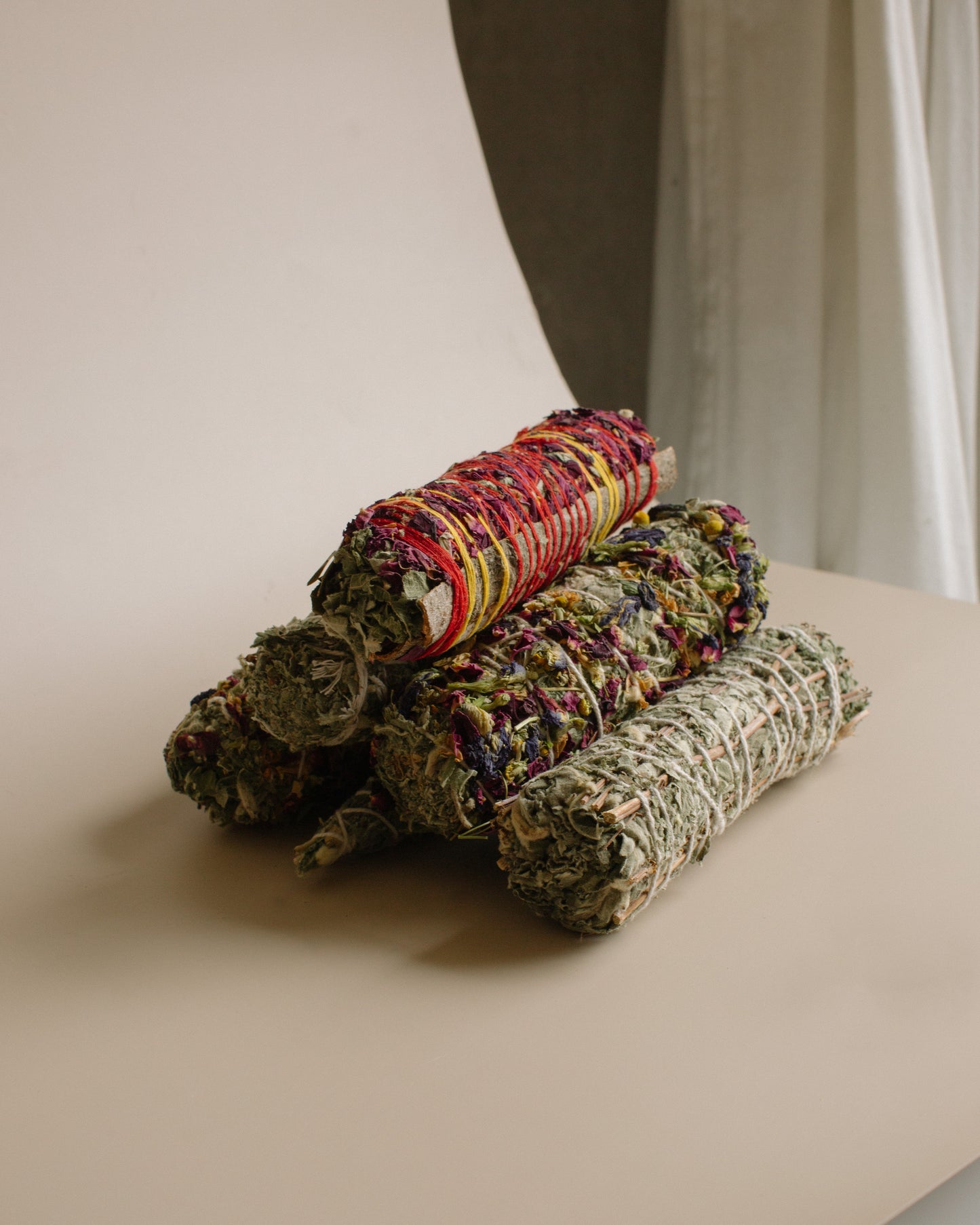 Three rolled-up items, possibly incense or fabric, on a light surface with a neutral background.