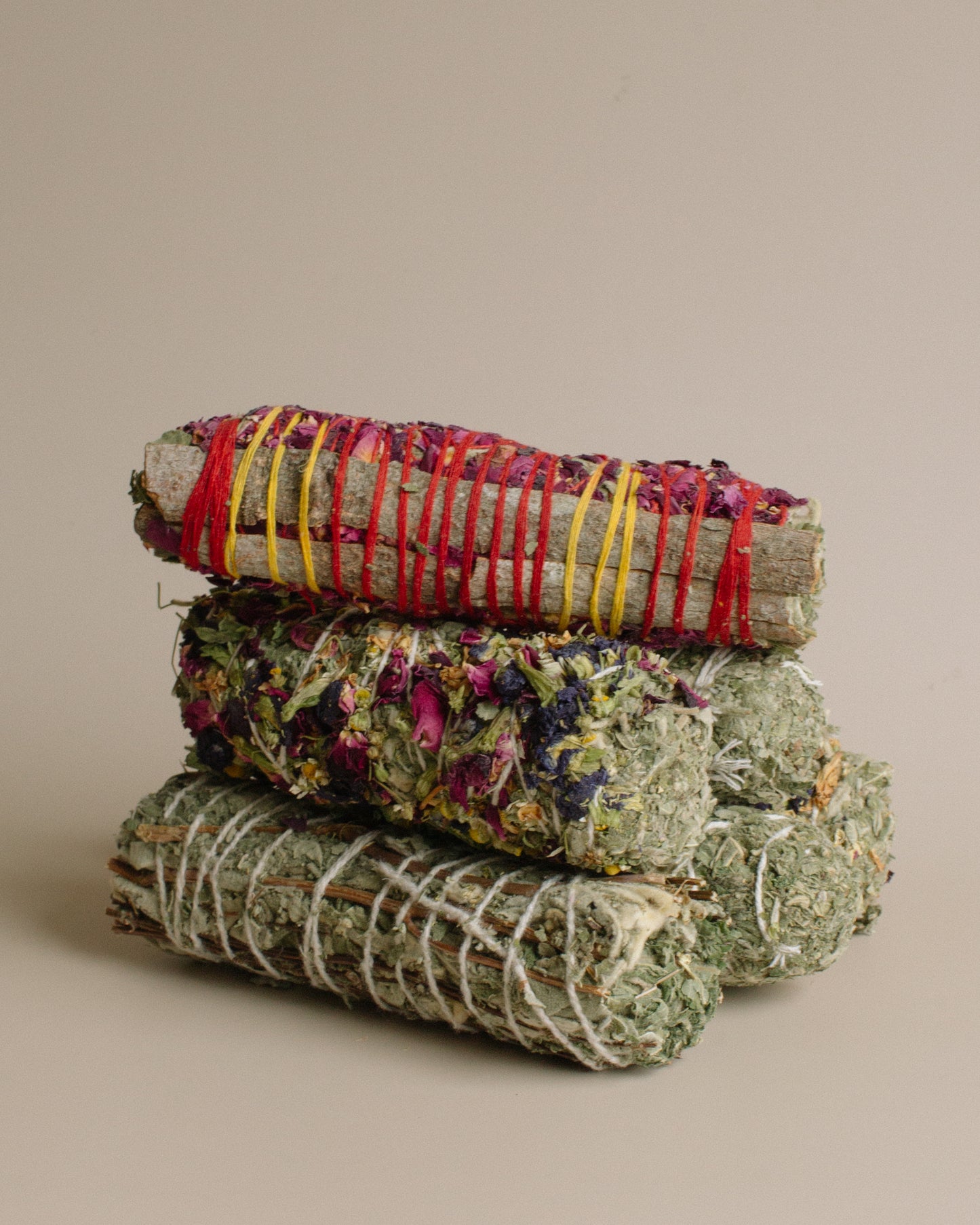 Stack of dried herb bundles tied with colorful string on a beige background