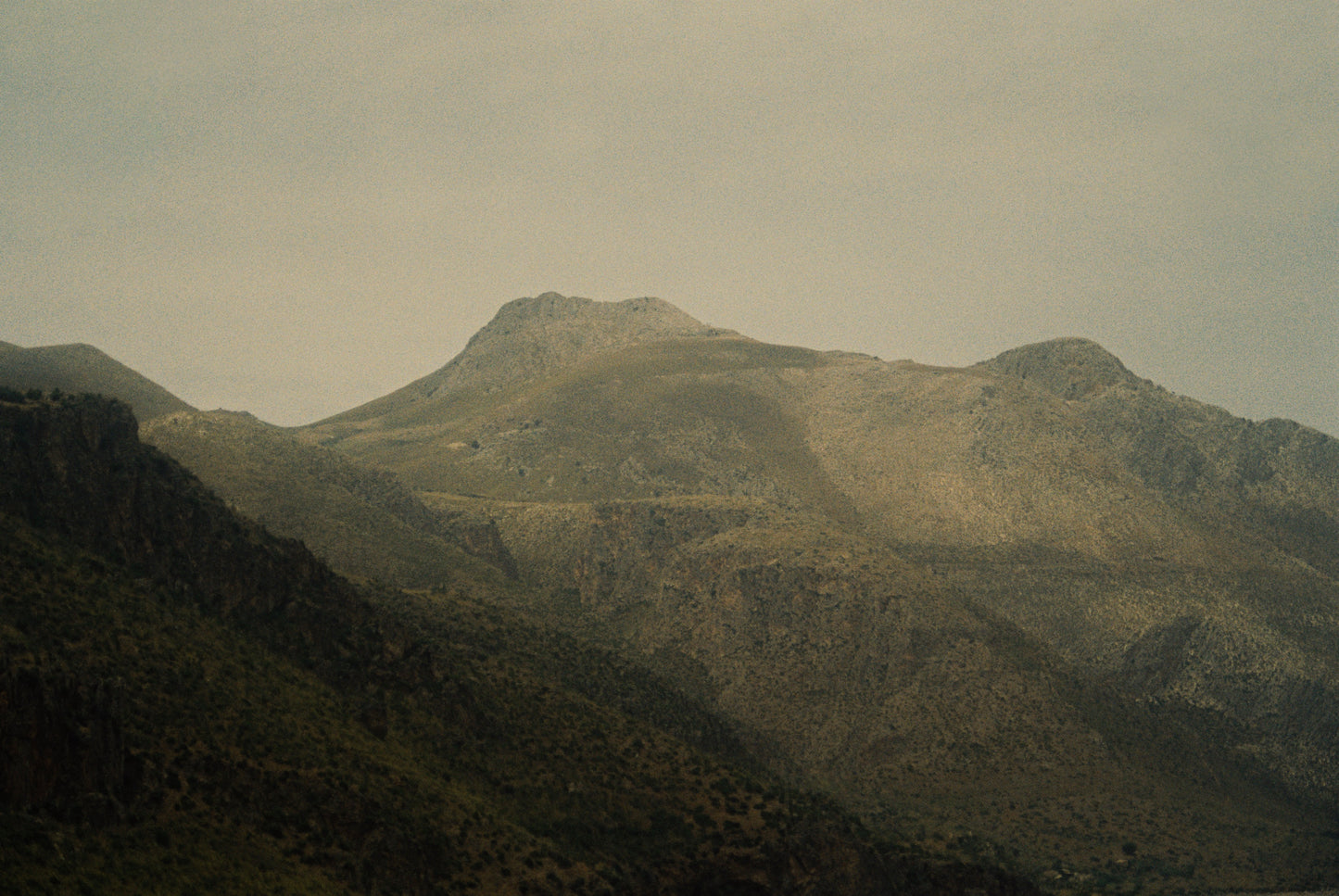 Hazy Himalayan mountain landscape with rolling hills and a misty sky