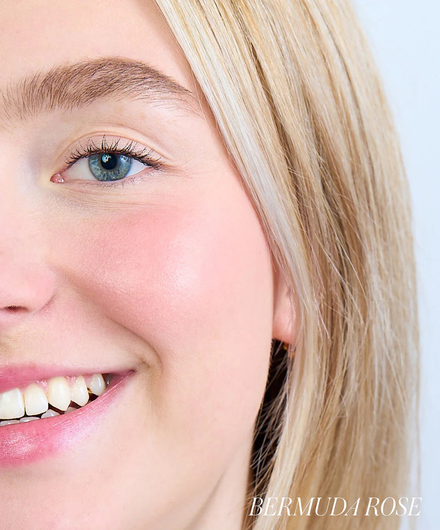 Close-up of a person with blonde hair and blue eyes, wearing 'Bermuda Rose' makeup.
