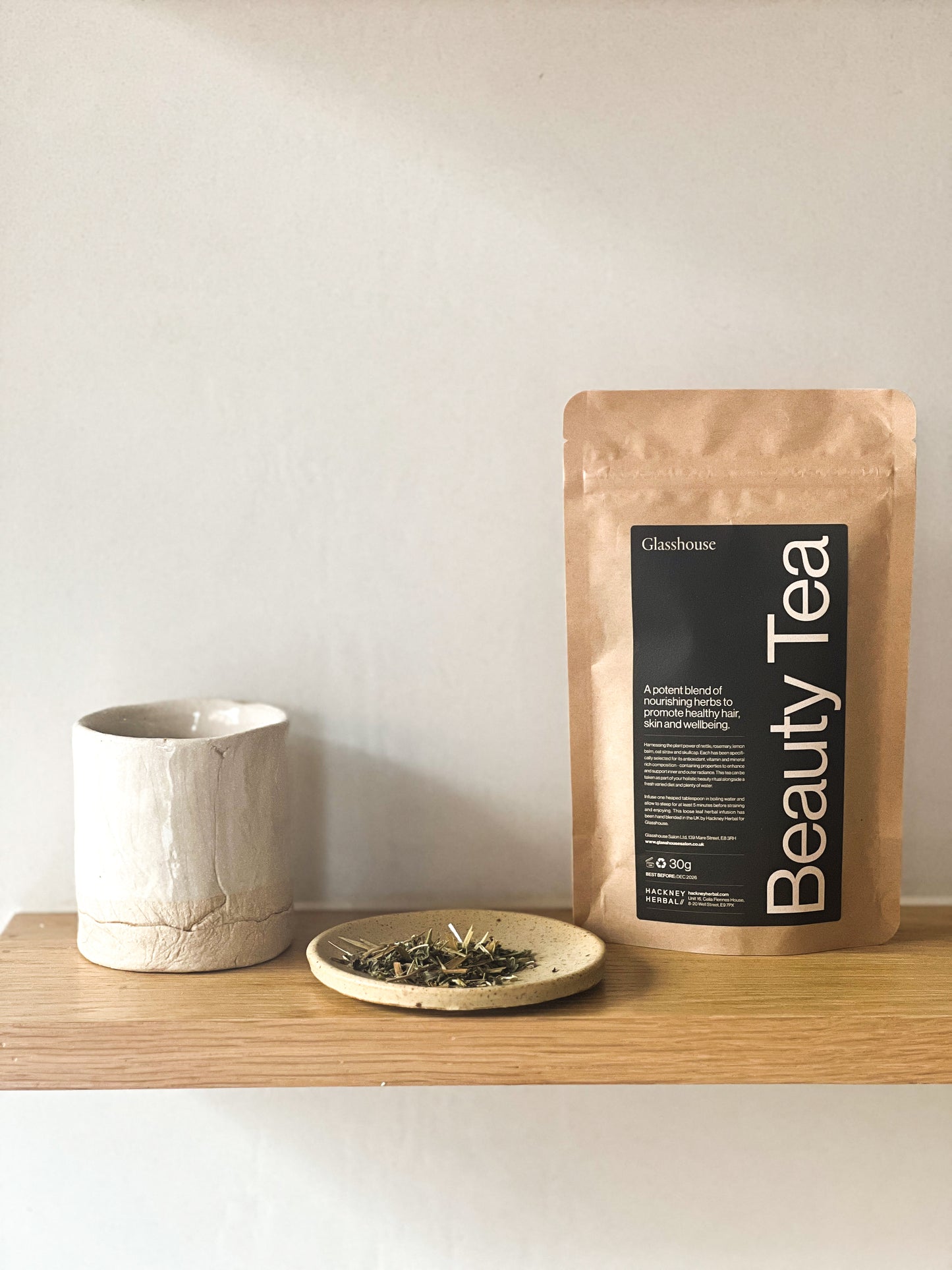 Beauty Tea package on a wooden shelf with a ceramic cup and saucer.