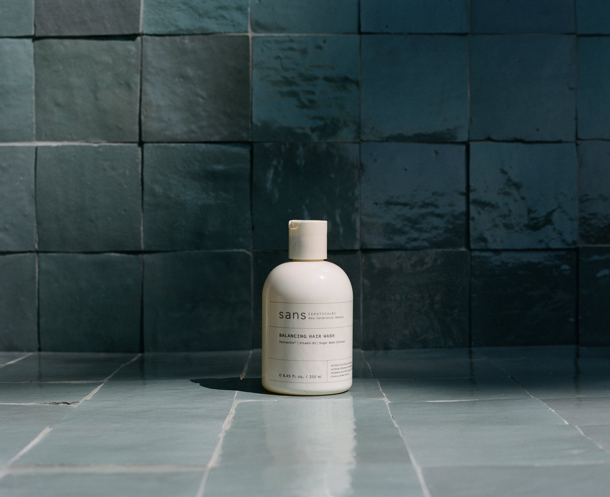 Bottle of 'sans' product on a tiled floor with dark blue tiles in the background
