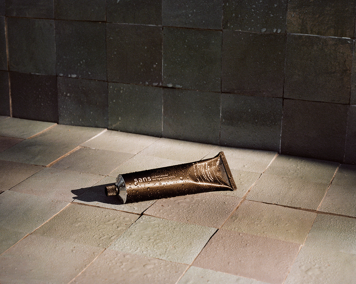 Tube product on a tiled floor against a dark tiled wall