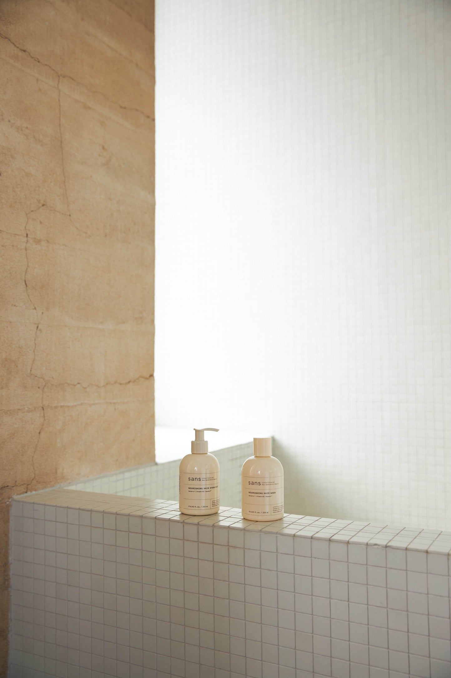 Two bottles on a tiled ledge with a neutral wall background