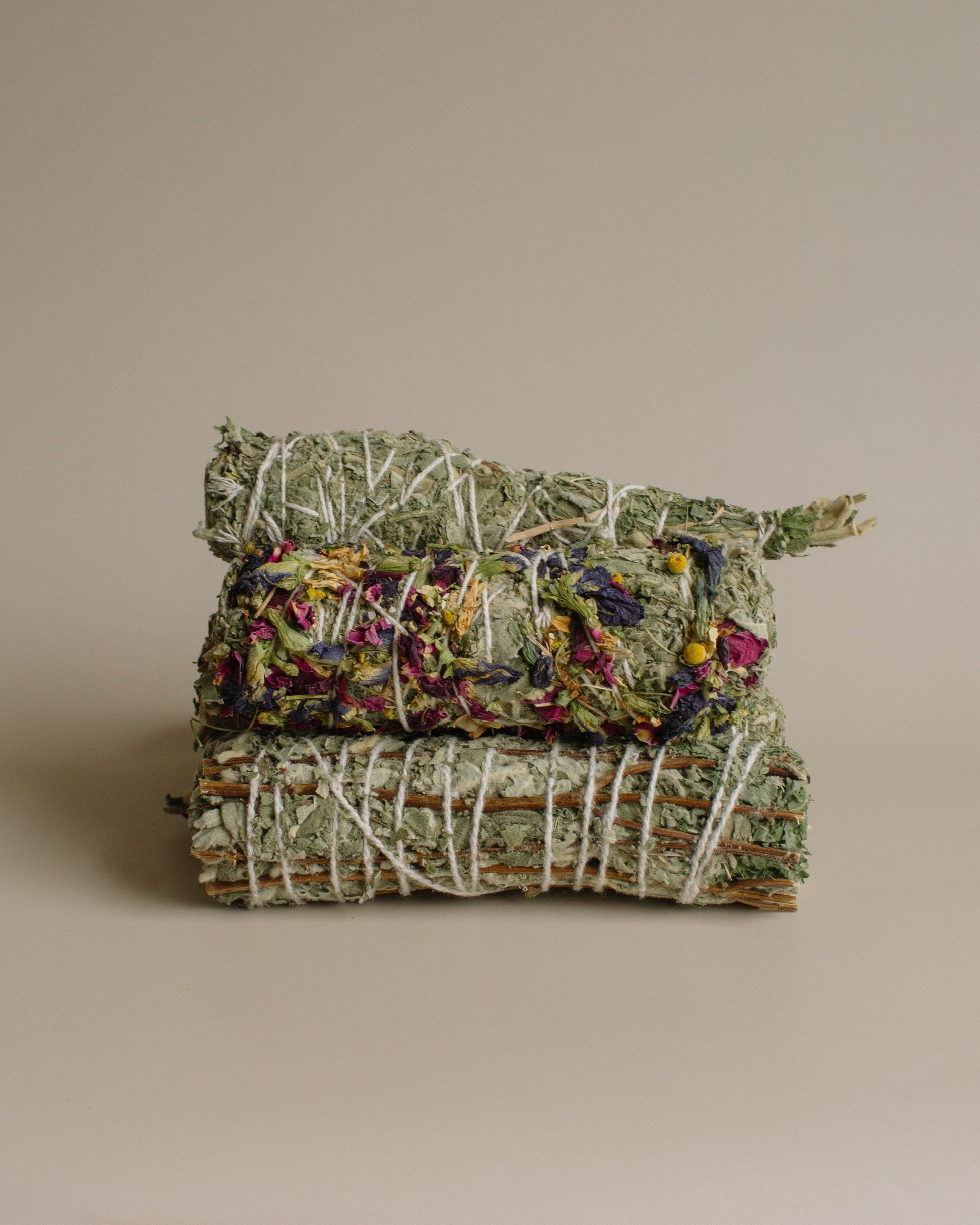 Stack of Sage and variations of smoke bundles stacked on a beige background