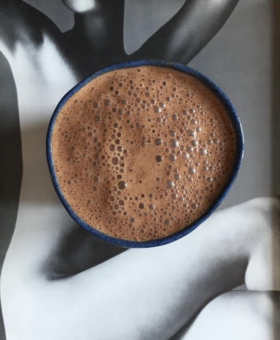 Close-up of a cup of cacao held by a person with a neutral background