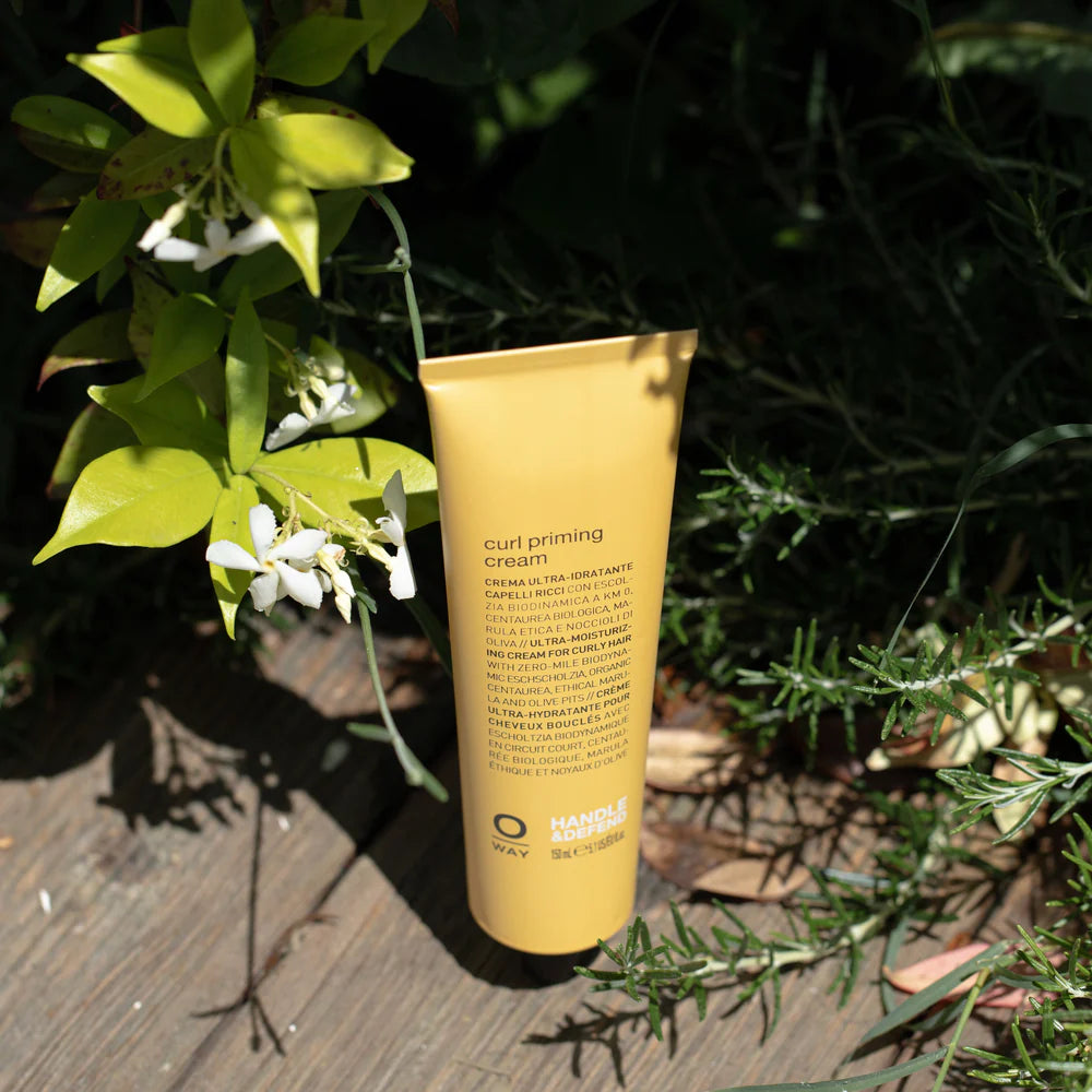 Tube of curl priming cream hair styling product by OWAY on a wooden surface with Botanicals
