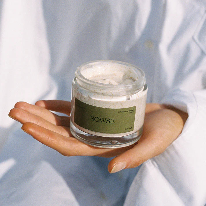 Hand holding a jar of cream labeled 'ROWSE' against a light background