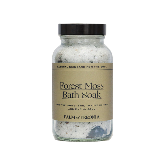Forest Moss Bath Soak by Palm of Feronia, Natural skincare for the soul, bath soak in glass jar 600g A clear glass jar containing a mix of white and grey bath soak with a label that reads 'Forest Moss bath soak' and the brand name 'Palm of Feronia'. The jar has a black lid and is labeled as a 'Natural Skincare Product for the Soul'.