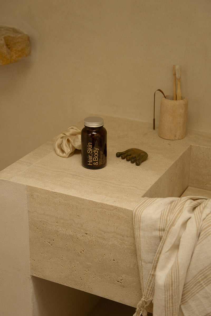 Glasshouse Hair Skin and Body Supplement on stone bathroom sink
