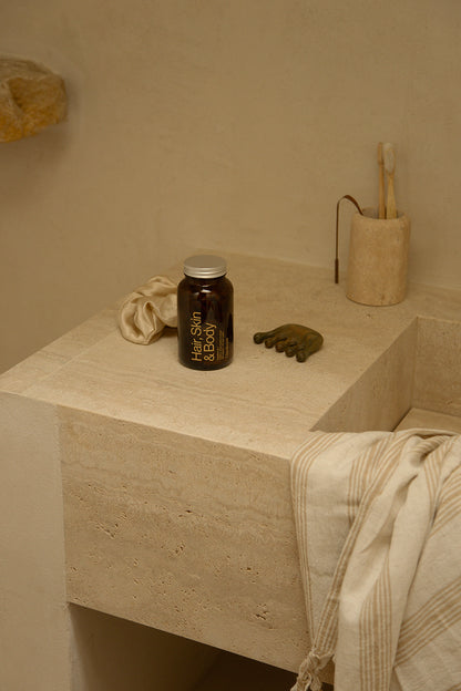 Glasshouse Hair Skin and Body Supplement on stone bathroom sink