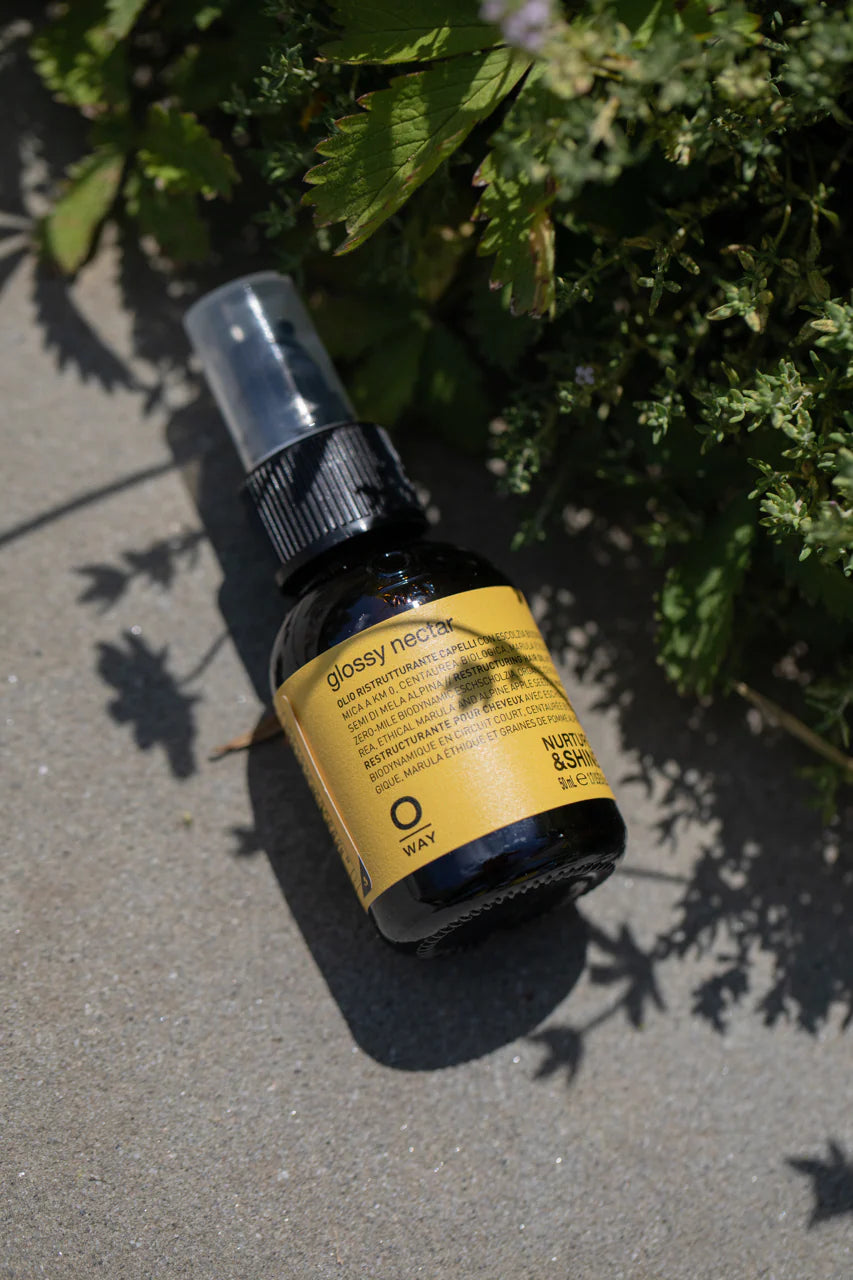 Glossy Bio bottle by OWAY on a concrete surface with greenery in the background