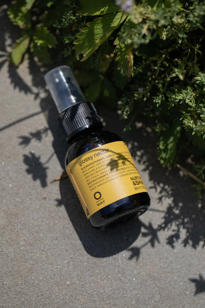 Glossy Bio bottle by OWAY on a concrete surface with greenery in the background