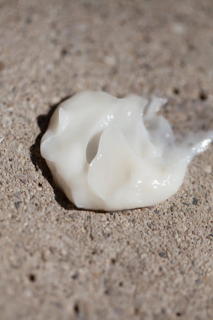 White creamy product Curl Priming Cream by OWAY on a textured beige surface
