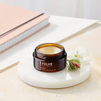 Jar of Evolve Organic Beauty lip balm on a white surface with a flower
