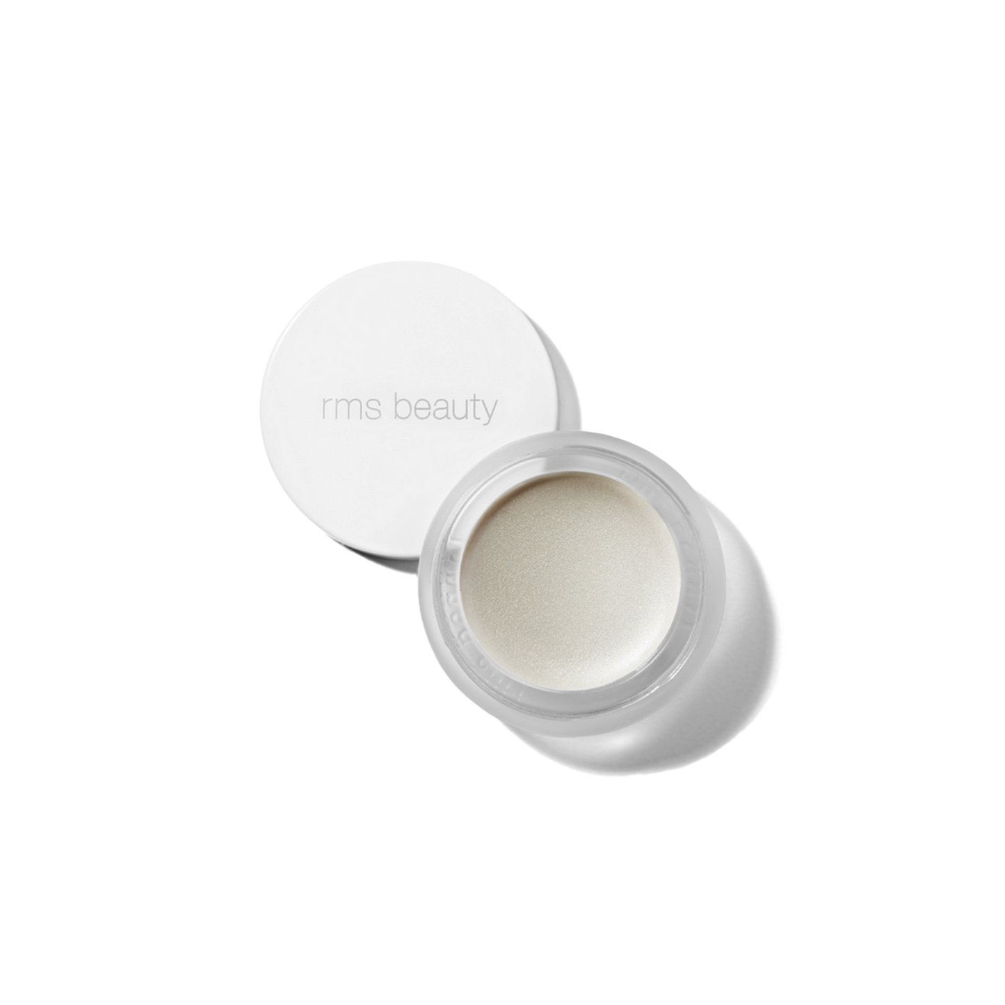 A small, white, round container with a lid, open, showing a beige-colored cosmetic product inside, presumably the RMS Luminizer highlighter.