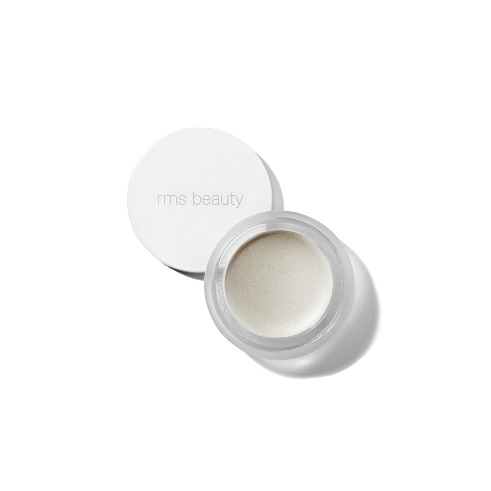 A small, white, round container with a lid, open, showing a beige-colored cosmetic product inside, presumably the RMS Luminizer highlighter.