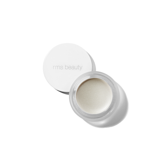 A small, white, round container with a lid, open, showing a beige-colored cosmetic product inside, presumably the RMS Luminizer highlighter.