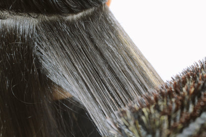 Close up of dark brown hair being blowdried and brushed.