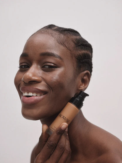 Woman holding a cosmetic product with a plain background