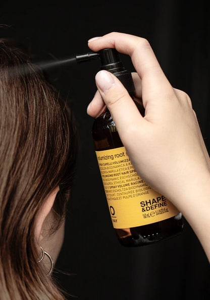 Person using a hair product labeled 'Shape & Define' on dark background
