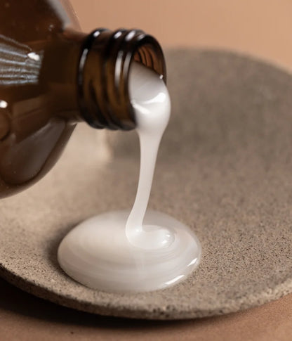 Smooth'n Glow Hair Bath shampoo 240mls by OWAY being poured onto natural dish