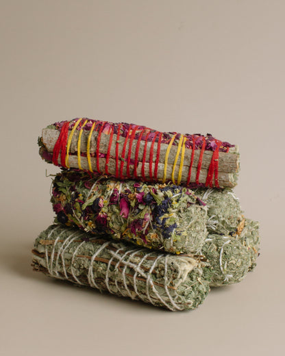 Stack of dried herb bundles tied with colorful string on a beige background