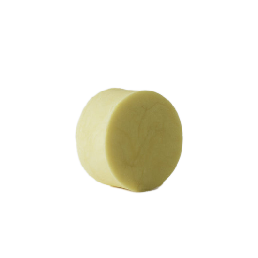 A cream coloured shampoo bar on a white baground