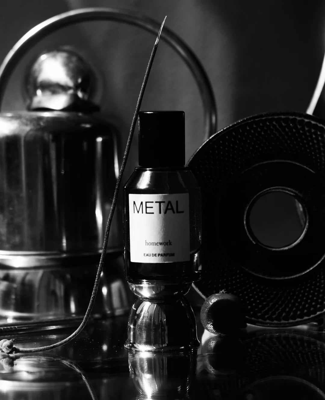 Bottle of perfume labeled 'Metal' with decorative elements in a black and white setting.
