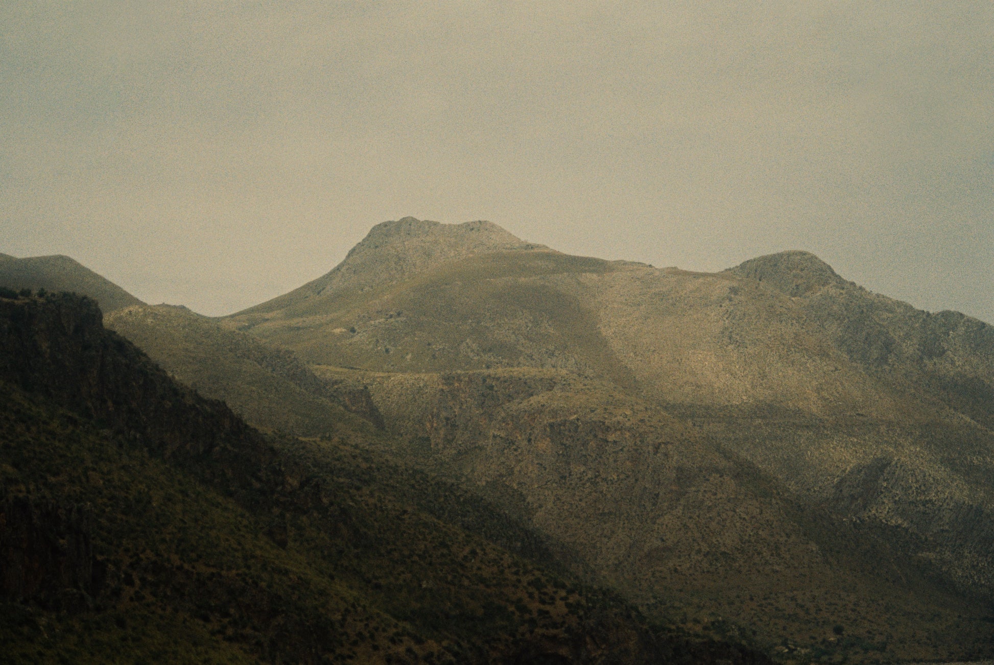 Hazy Himalayan mountain landscape with rolling hills and a misty sky