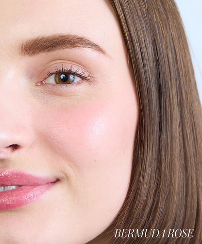 Close-up of a person's face with visible makeup, including eyeliner and blush, with 'Bermuda Rose' branding.